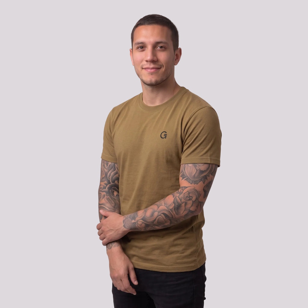 A man modelling an army colour t-shirt with a black embroidered ‘Clobber & Gear’ logo on the left chest, paired against a light grey studio background.