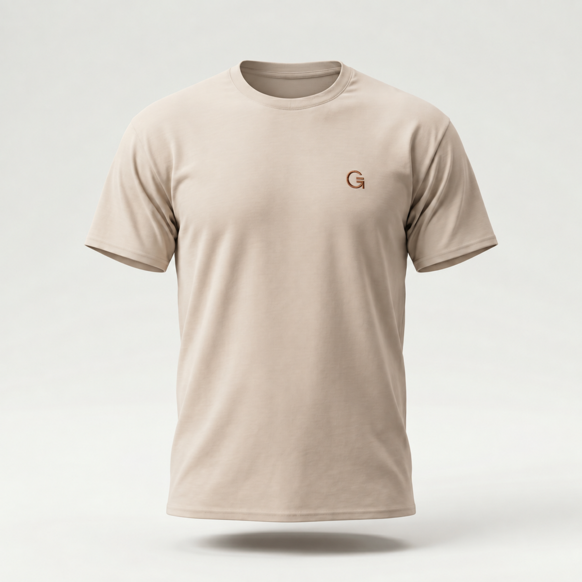 A ghost mannequin showing a sandstone short-sleeve t-shirt with a russet “Clobber & Gear” logo embroidered on the left chest, set against a gradated grey background.