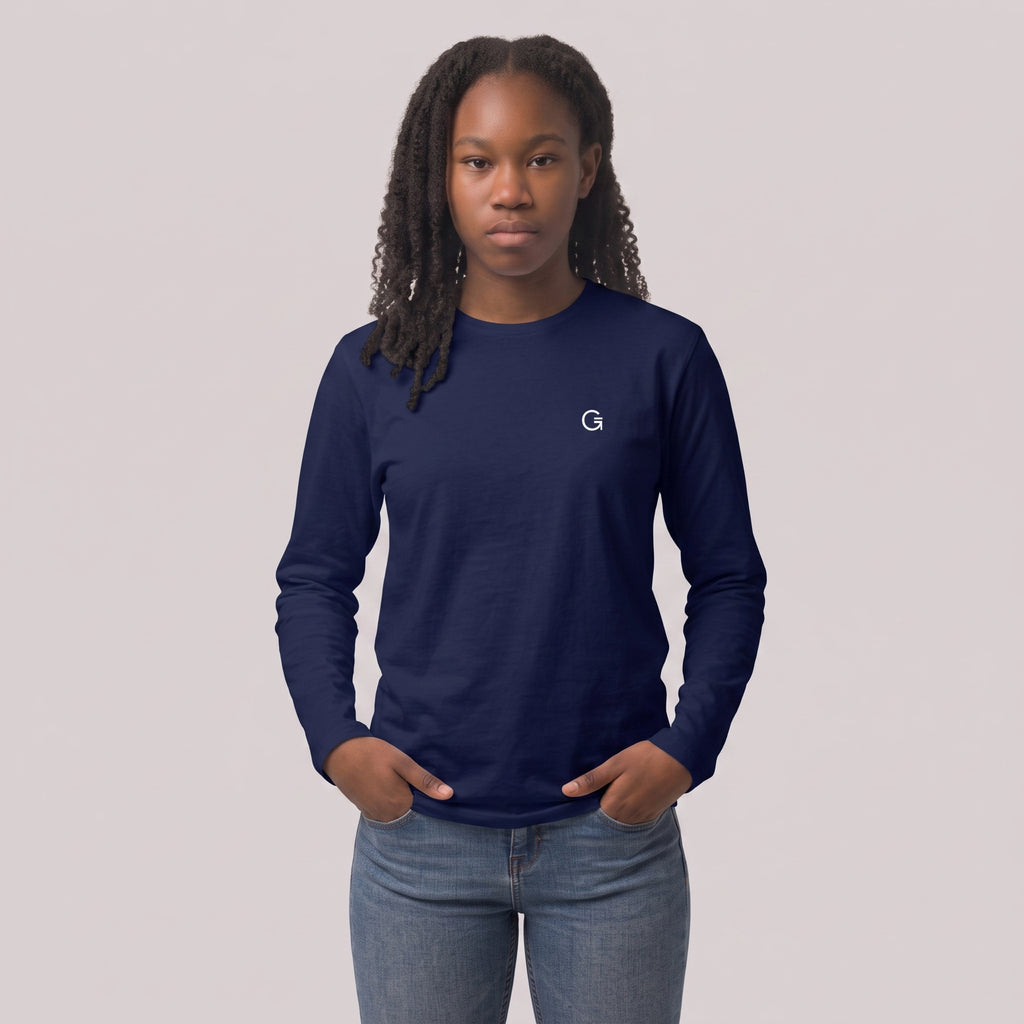 A woman modelling a navy blue long sleeved t-shirt with a white embroidered ‘Clobber & Gear’ logo on the left chest, paired against a light grey studio background.