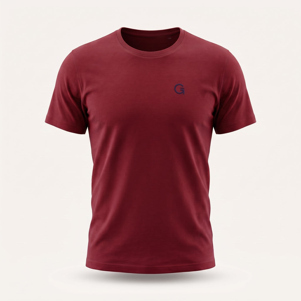A ghost mannequin image of a brick red crew-neck t-shirt with a navy blue “Clobber & Gear” logo embroidered on the left chest, displayed on a neutral light grey background.