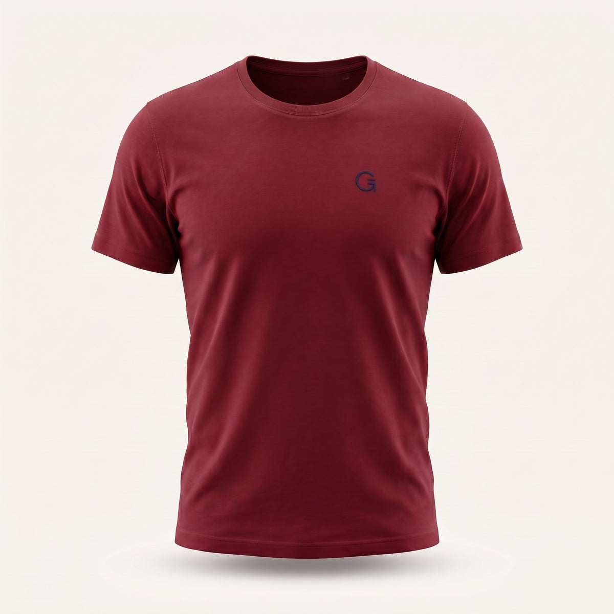A ghost mannequin image of a brick red crew-neck t-shirt with a navy blue “Clobber & Gear” logo embroidered on the left chest, displayed on a neutral light grey background.