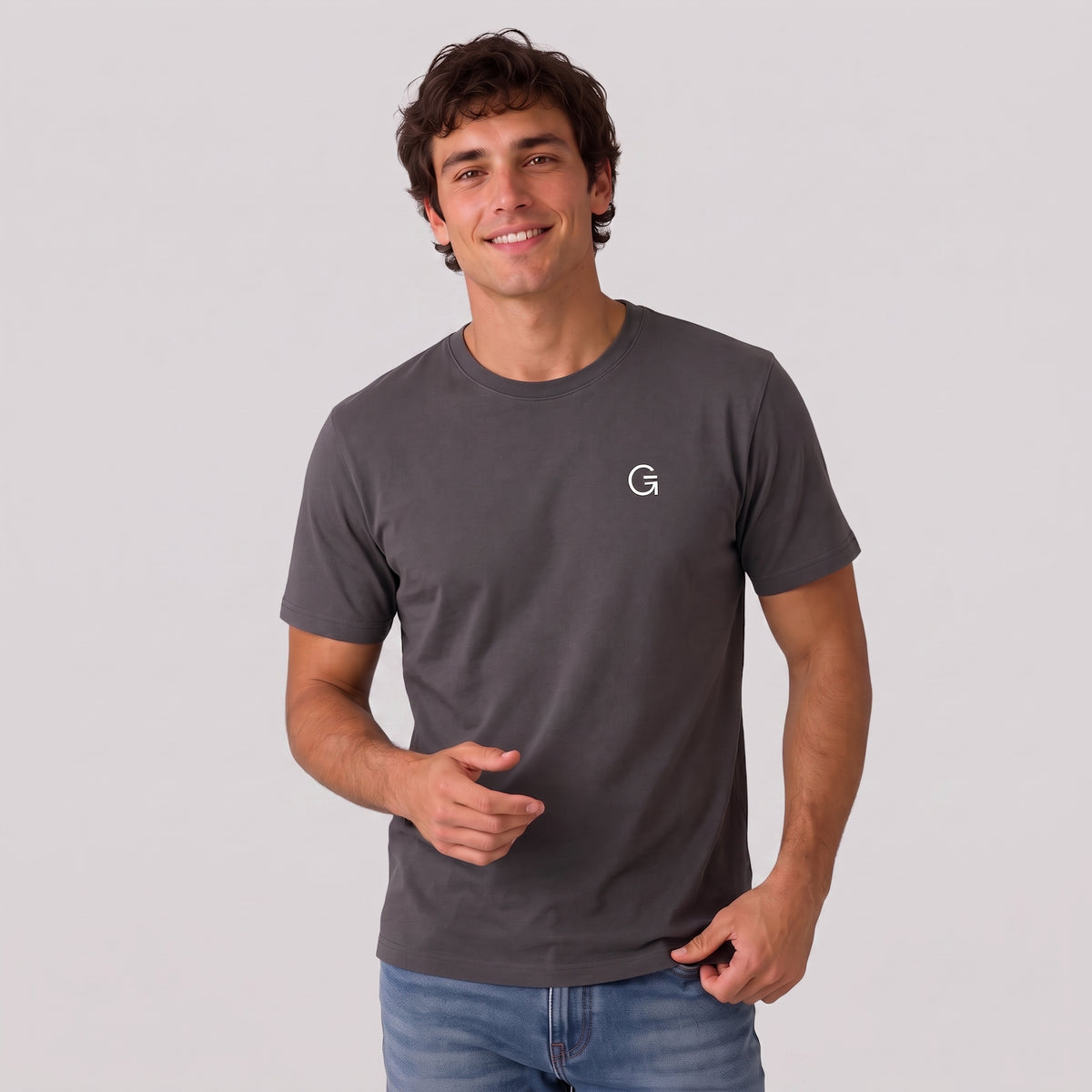 A man modelling a charcoal tee with a white embroidered ‘Clobber & Gear’ logo on the left chest, paired against a light grey studio background.