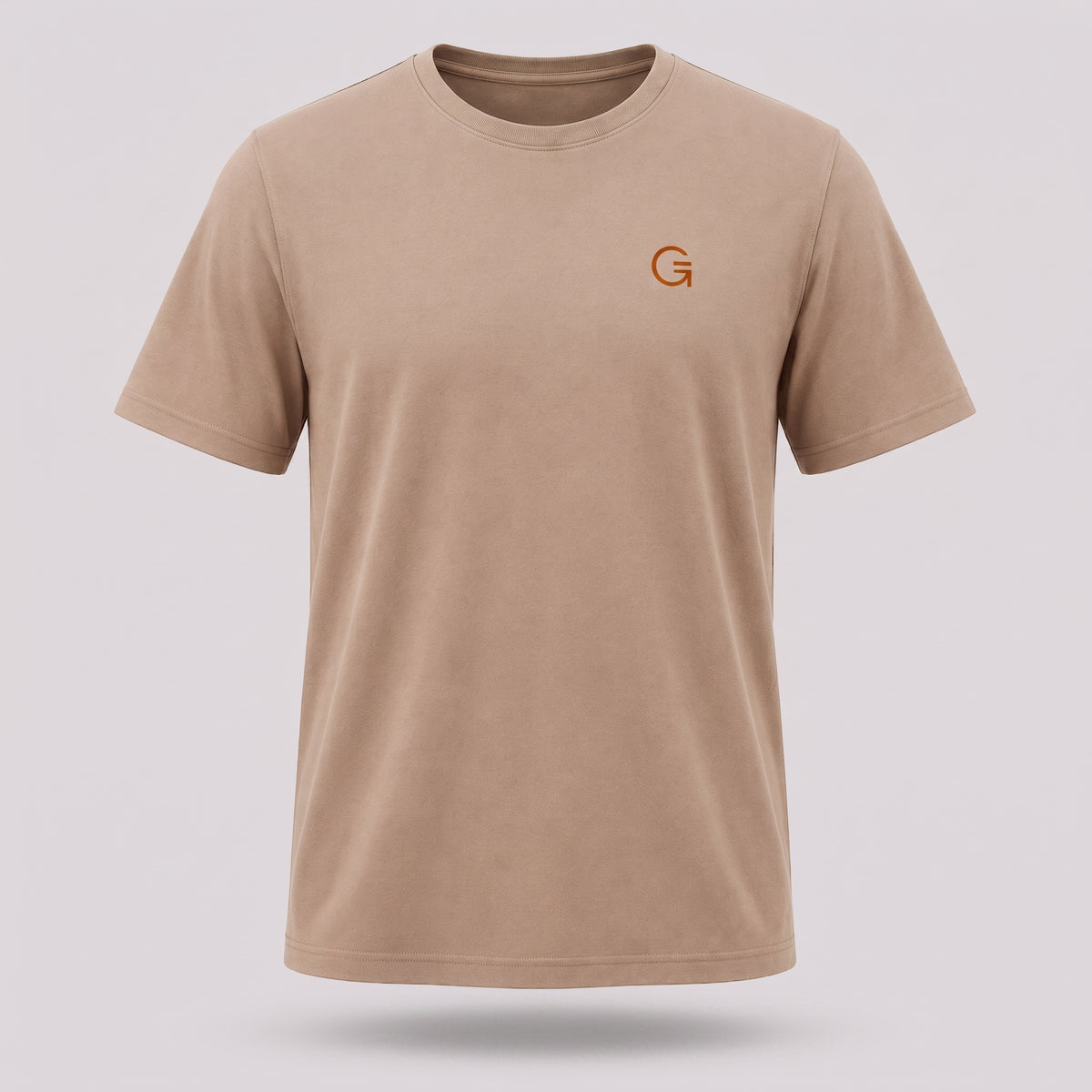 A ghost mannequin image of a latte-coloured crew-neck t-shirt with a burnt orange “Clobber & Gear” logo embroidered on the left chest, displayed on a neutral light grey background.