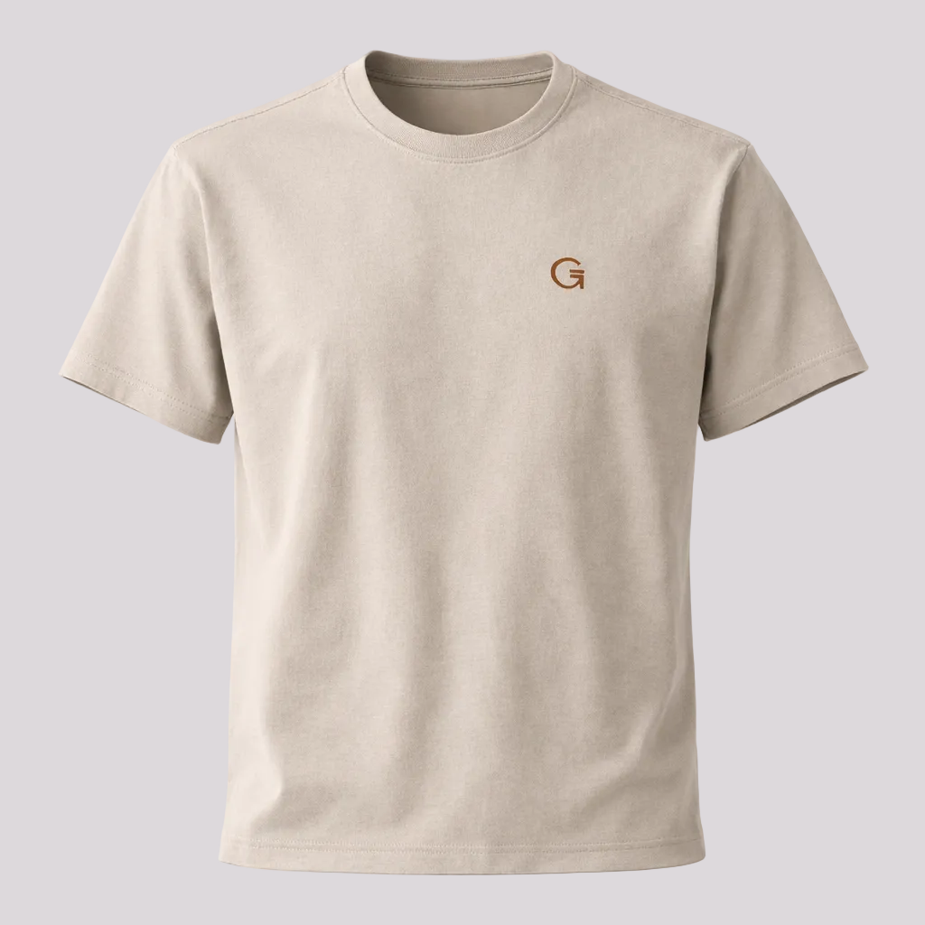 A light sand crewneck short-sleeve t-shirt with a russet brown-coloured ”Clobber & Gear” logo embroidered on the left chest, displayed against a plain light grey background.