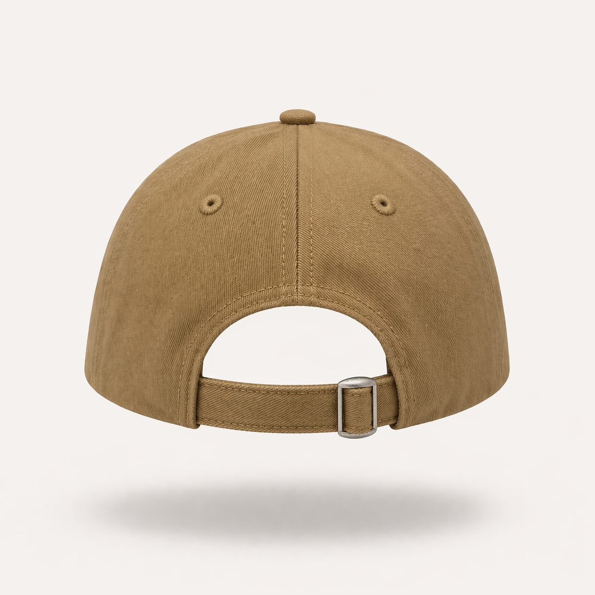 Rear view of a tan baseball cap featuring an adjustable fabric strap with a silver metal tri-glide buckle, embroidered eyelets, and stitched paneling set against a plain light background.